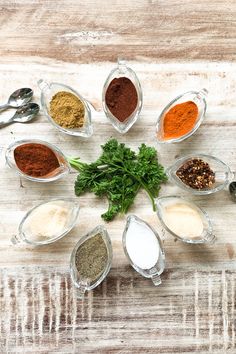 seven different spices arranged in the shape of a circle on top of a wooden table