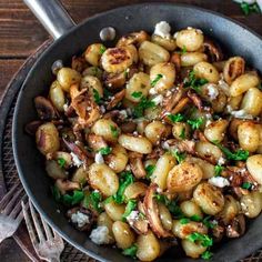 a pan filled with potatoes and mushrooms covered in parmesan cheese on top of a wooden table