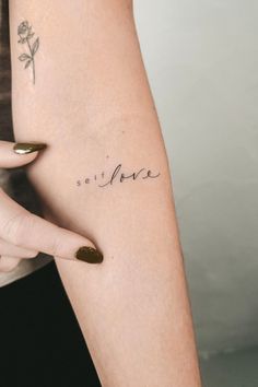 a woman's arm with the word love written on it and a rose tattoo