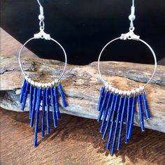 a pair of blue earrings sitting on top of a piece of wood