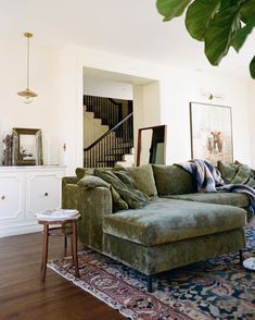 a living room filled with furniture next to a stair case in a white walled room