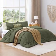 a bed with green comforters and pillows in a room next to a large window