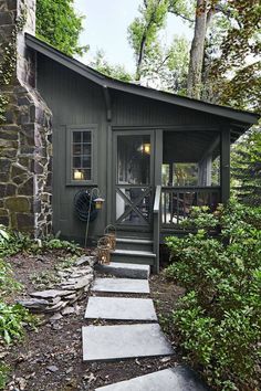 a small cabin in the woods with steps leading up to it's front door