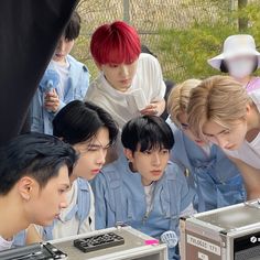 the group of young men are looking at their electronic devices in front of each other