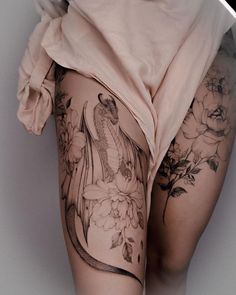 a woman's thigh with tattoos and flowers on it