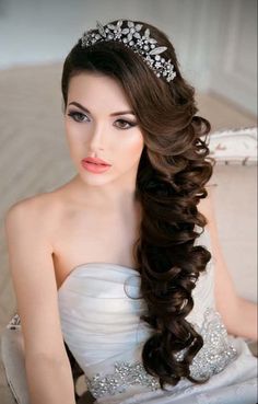 a woman with long hair wearing a tiara and sitting on a couch in a white dress