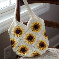 a crocheted sunflower bag hanging from a wooden chair next to a window