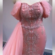 a pink evening gown on display in front of a mannequin