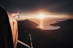 an airplane flying over the ocean at sunset