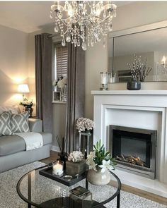 a living room filled with furniture and a chandelier hanging from the ceiling over a fire place