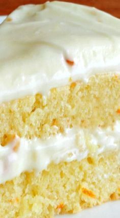 a close up of a slice of cake on a plate with white frosting and orange sprinkles