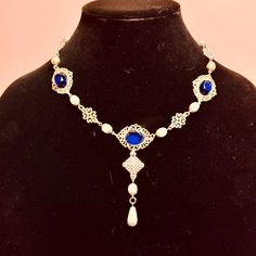 Handcrafted replica period jewelry, made to imitate the style and grandeur of the Tudors. This elegant necklace will complement any renaissance garb, and elevate even the most simple gown into a piece fit for a queen. It is made to order in your choice of gold, silver, or bronze and can be set with resin gemstones of just about any color. Ruby, emerald, sapphire, amethyst and onyx are most popular options. It is accented with beautiful mix of pearls sandwiched between matching metal bead caps, and metal filigree pieces. A teardrop pearl dangles beautifully in front. Baroque Necklace With Historical Design For Weddings, Baroque Necklaces With Historical Design For Wedding, Elegant Baroque Necklace With Historical Design, Baroque Historical Design Necklace For Wedding, Baroque Wedding Necklace With Historical Design, Baroque Necklace With Historical Design As A Gift, Elegant Costume Jewelry Choker, Baroque Historical Design Necklace For Gift, Elegant Historical Pendant Necklaces