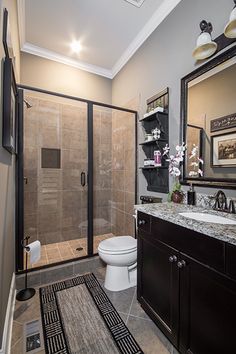 a bathroom with a walk in shower next to a white toilet and black cabinetry