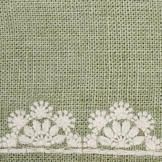 an embroidered piece of cloth with white flowers and leaves on green fabric, closeup