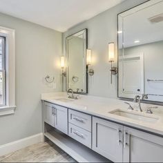 a bathroom with double sinks and mirrors in the corner, along with two lights on either side of the window