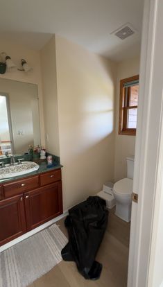 a black trash bag sitting in the middle of a bathroom next to a white toilet