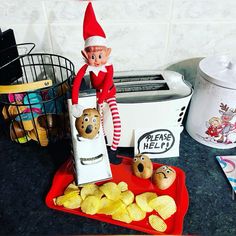 an elf is sitting on top of the toaster next to some potato chips and bread