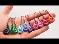 a hand holding five different colored necklaces in it's palm, with one being held by the other