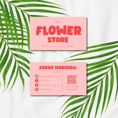 two business cards with palm leaves and the flower store logo in red on pink background