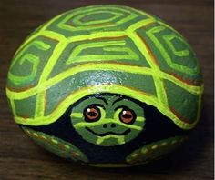 a turtle painted on top of an orange and green ball with a black face in the shape of a turtle