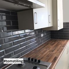 a kitchen with white cabinets and wood counter tops in front of a stove top oven