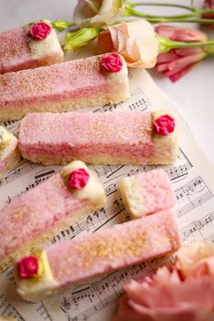 some kind of cake with pink flowers on top of sheet music notes and roses in the background