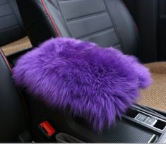 a purple furry pillow sitting on top of a car seat