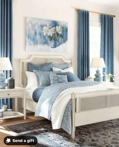 a bedroom with blue curtains and white furniture