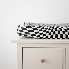 a black and white checkered blanket sitting on top of a dresser next to a drawer