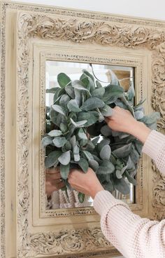 a woman holding a plant in front of a mirror