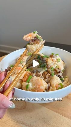 a woman holding chopsticks over a bowl of food with meat and vegetables in it