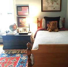 a teddy bear sitting on top of a bed in a room with an american flag rug