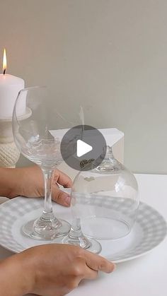 a person holding a wine glass on top of a plate with a candle in the background