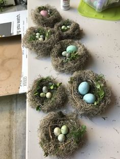 four small nests with eggs in them on a white table top next to a wooden box