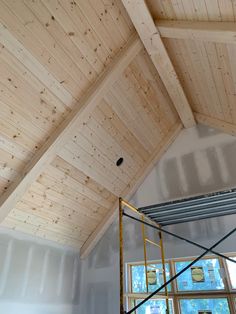 an unfinished room with wooden walls and beams on the ceiling is being worked on by a scaffolder