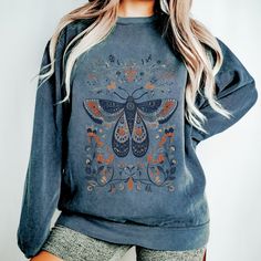 Indulge in the warmth and charm of our cozy sweatshirt featuring a captivating Scandinavian folk-art-inspired moth illustration. Crafted with comfort in mind, this unique and stylish piece effortlessly combines snug vibes with a touch of Nordic whimsy, making it a must-have for those who crave both comfort and distinctive style. The Comfort Colors 1555 sweatshirt offers a relaxed and laid-back fit, providing a comfortable and effortlessly cool look. Its loose silhouette and soft fabric make it the perfect go-to piece for a cozy, easygoing style that embraces comfort without sacrificing fashion. .: Unisex Style .: 80% ringspun cotton, 20% polyester .: Medium-heavy fabric  .: Relaxed fit .: Sewn in twill label .: OEKO-TEX-certified low-impact dyes Care: *Separate darks and light, ESPECIALLY Winter Cottagecore Long Sleeve Tops, Hippie Crew Neck Top For Fall, Bohemian Cotton Sweater For Fall, Bohemian Long Sleeve Sweatshirt For Winter, Bohemian Long Sleeve Relaxed Fit Sweater, Cottagecore Cotton Sweater For Fall, Bohemian Crew Neck Sweatshirt For Fall, Bohemian Winter Tops With Graphic Print, Cottagecore Long Sleeve Tops For Fall