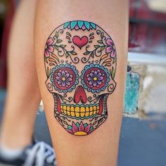 a woman's leg with a colorful sugar skull tattoo on it