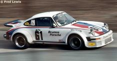 a white porsche racing car driving down a race track