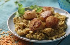 a white plate topped with rice and scallops on top of a blue table cloth