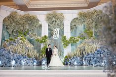 a bride and groom standing in front of an elaborate floral backdrop at their wedding reception