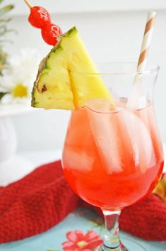 a pineapple drink in a glass with a straw and cherry garnish on the rim