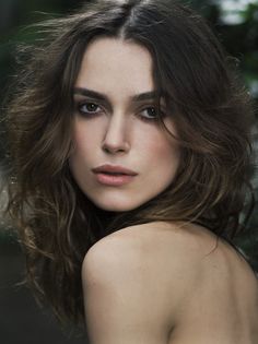 a close up of a woman with long hair and brown eyes looking at the camera