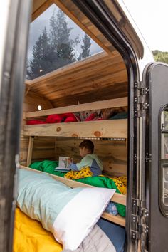 a man sitting on top of a bunk bed in the back of a truck with its door open