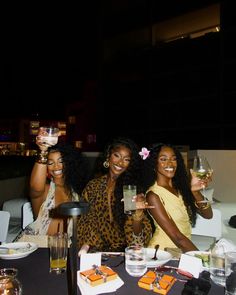 three women sitting at a table holding wine glasses