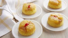 four small pastries on white plates sitting on a table