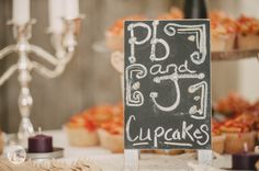 a chalkboard sign that says pb and j cupcakes with candles in the background