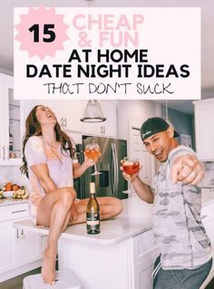 a man and woman sitting on top of a kitchen counter with drinks in their hands