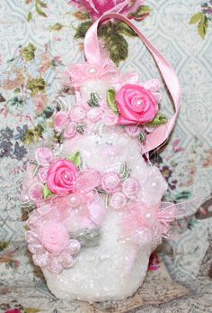 a white vase filled with pink flowers on top of a table