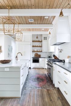 a kitchen with white cabinets and wood floors, along with an area rug on the floor