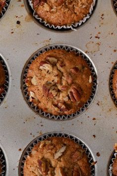 several muffins are in the pan with nuts on top